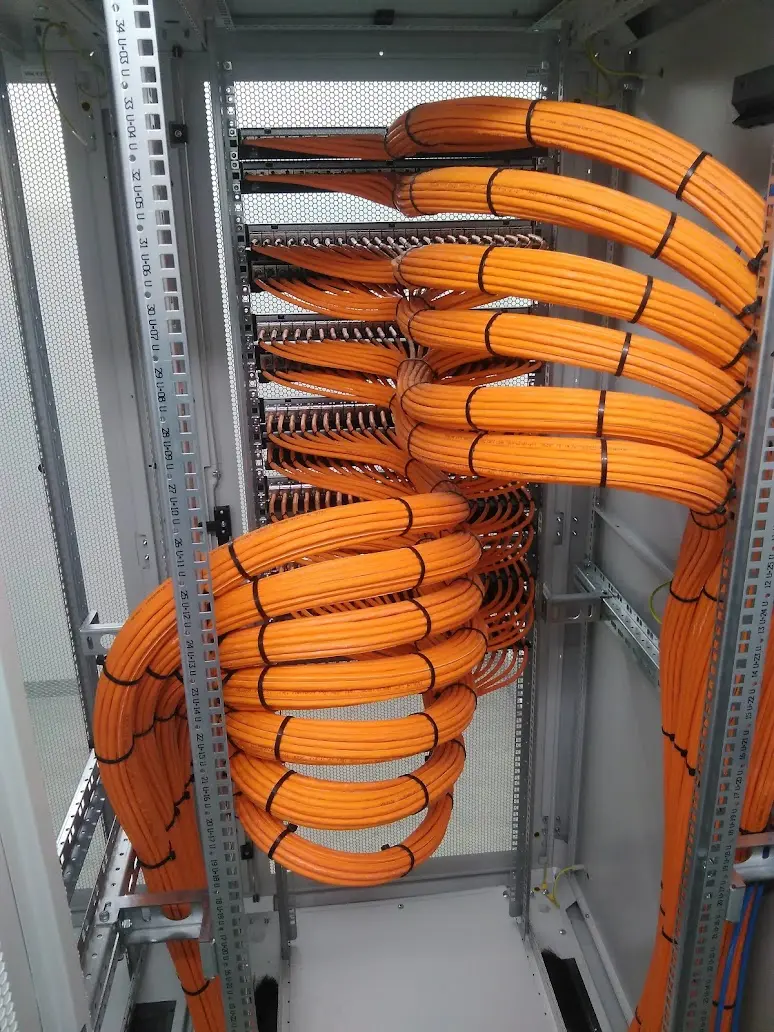 Rückseite eines Patchfeldes mit strukturierter orangefarbener Kupferverkabelung